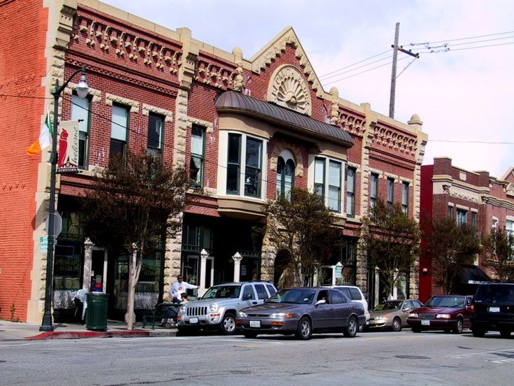 cars are parked on the side of the road in front of an old brick building