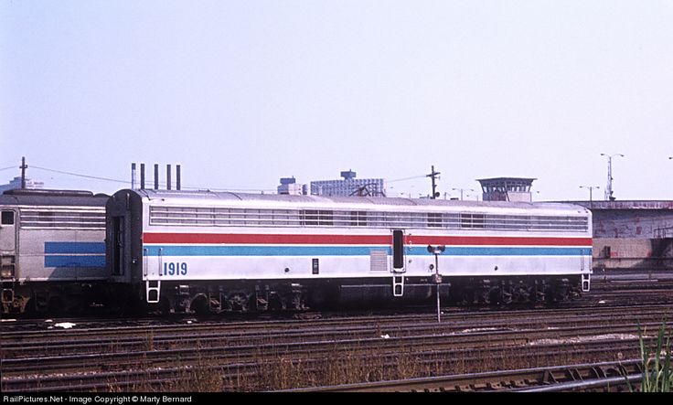 the train is traveling down the tracks near an industrial area with buildings in the background