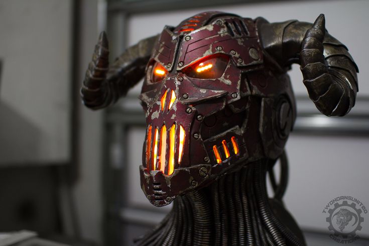 a close up of a robot head with glowing eyes and spikes on it's head