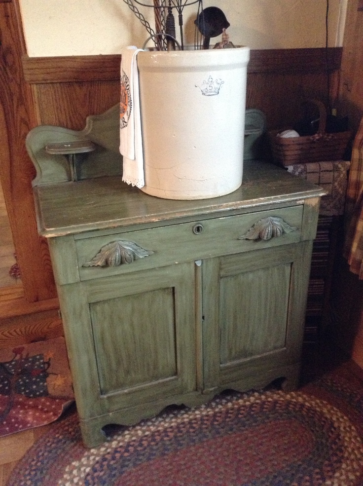 an old green cabinet with a white bucket on top and flowers in the bottom drawer