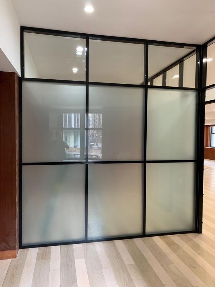 an empty room with glass walls and wood floors