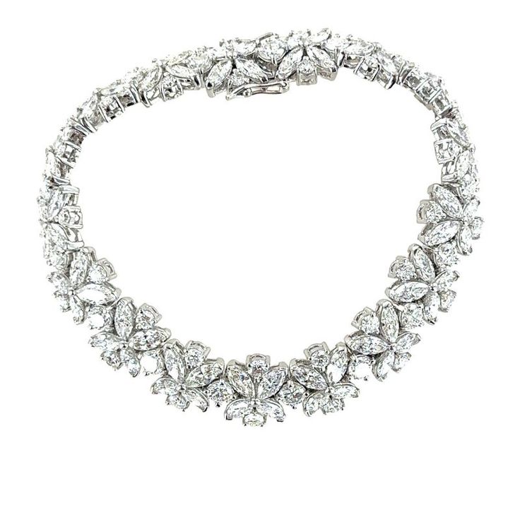 This platinum diamond estate bracelet is adorned with round brilliant and marquise diamonds to create a timeless and exquisite piece of jewelry. The combination of round brilliant and marquise diamonds features a captivating contrast of shapes and textures, creating a floral inspired design. The high quality diamonds weigh approximately 20 carat total weight and are graded G-H color and VS2-SI1 clarity. The bracelet measures 7.00 inches in length, .40 inches in width box clasp with 2 safety clasps. Stamped PT900. Weight: 42.8 grams. Luxury Marquise Diamond Bracelet With Brilliant Cut, Luxury Marquise Brilliant Cut Diamond Bracelet, Luxury Diamond Bracelet With Marquise Cut, Formal Marquise Cut Diamond Bracelet, Marquise Cut Diamond Bracelet For Formal Occasions, White Gold Marquise Cubic Zirconia Diamond Bracelet, Formal Silver Marquise Diamond Bracelet, Luxury Marquise Diamond Tennis Bracelet, Marquise Diamond Bracelets With Diamond Accents