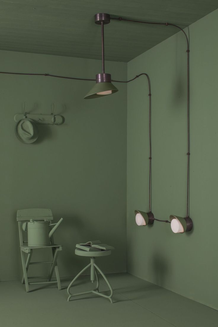 an empty room with green walls and two white chairs in front of the wall lights