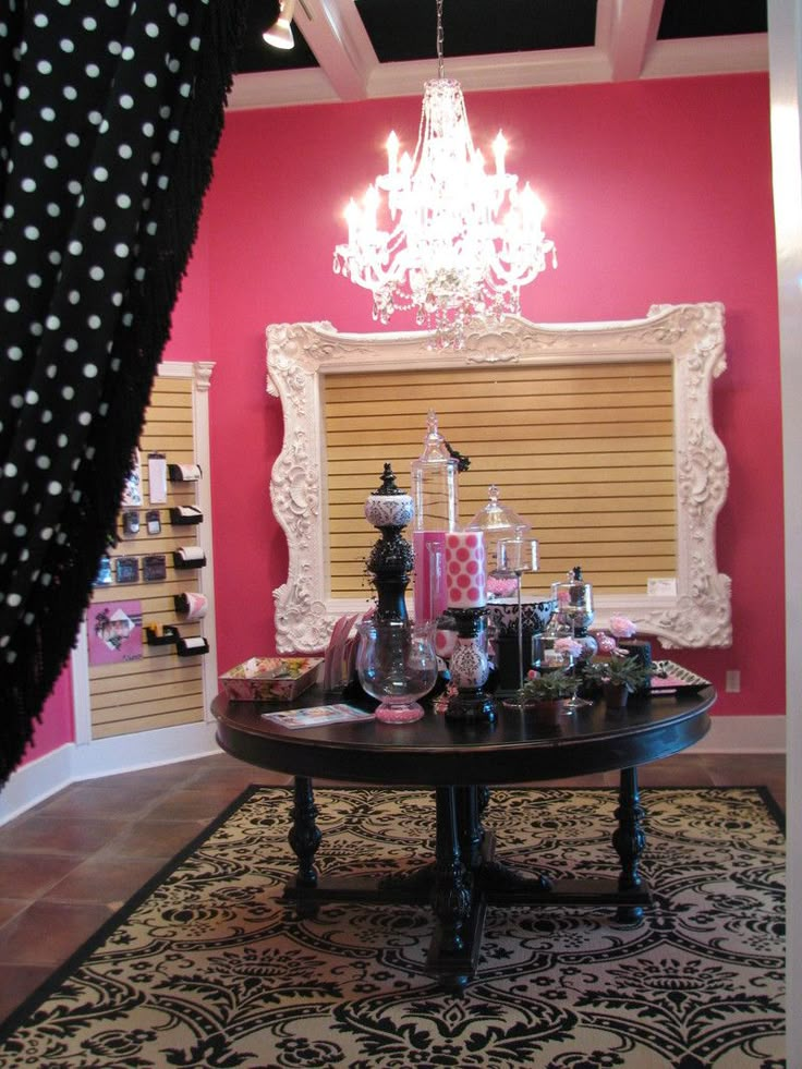 a room with a table, chandelier and window covered in curtains on the windowsill