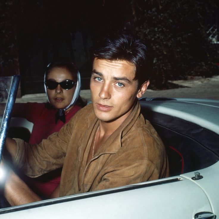 two people sitting in a car at night, one with a steering wheel and the other wearing sunglasses