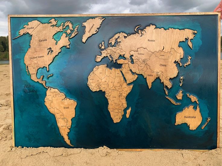 a large metal sign with a world map on it's side in the sand