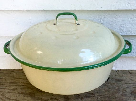 a white and green casserole sitting on top of a wooden table next to a wall