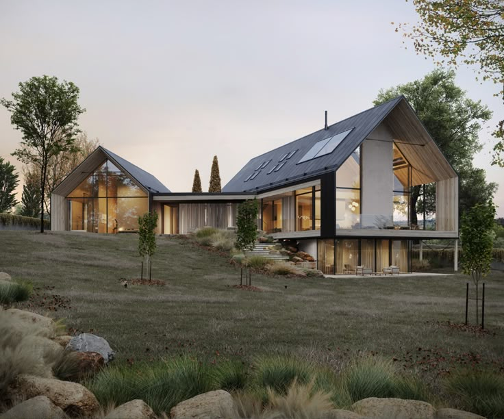 a modern house on top of a hill with trees in the foreground and grass to the side