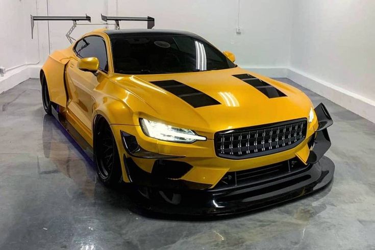 a yellow sports car with black stripes parked in a garage next to a white wall