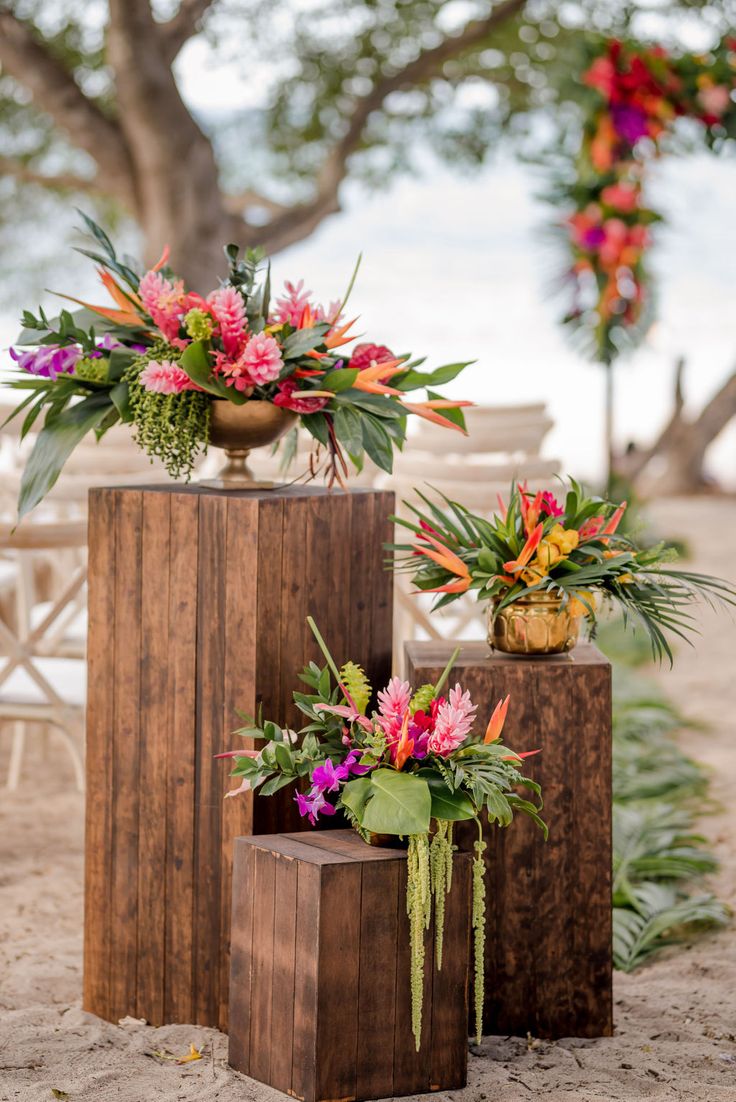 three wooden vases filled with colorful flowers and greenery