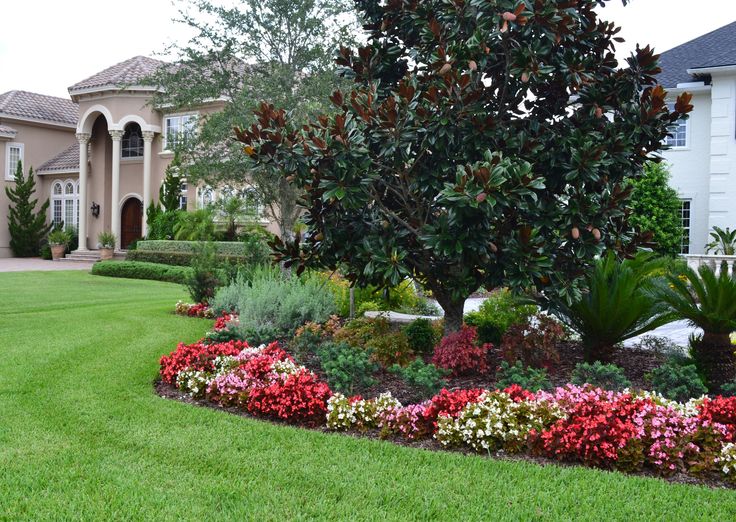 a large house with lots of trees and flowers in the front yard