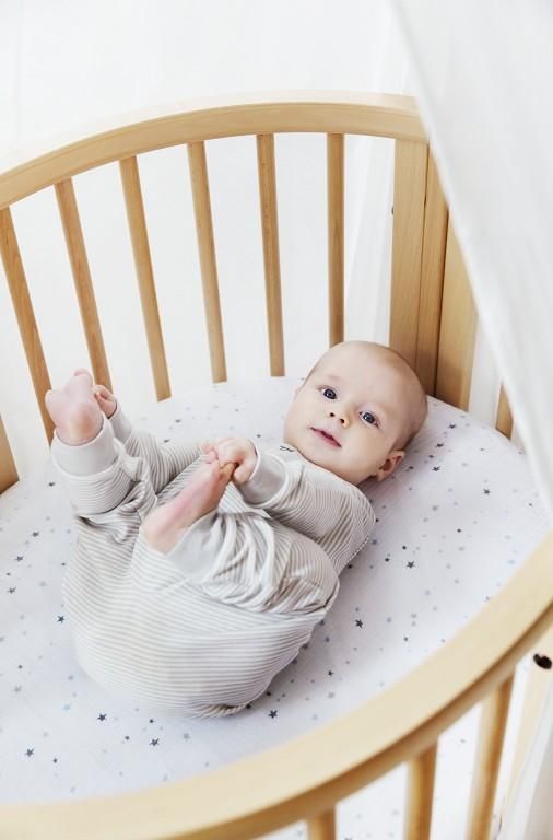 a baby laying in a crib looking up at the camera