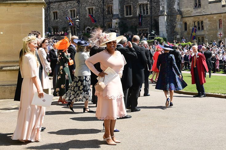 several women in dresses and hats are standing on the side walk near an old building