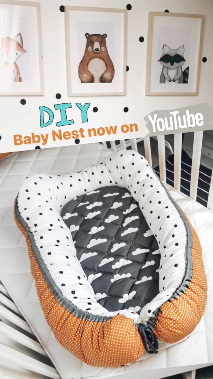 the baby nest is on display in front of pictures and an orange chair with black polka dot