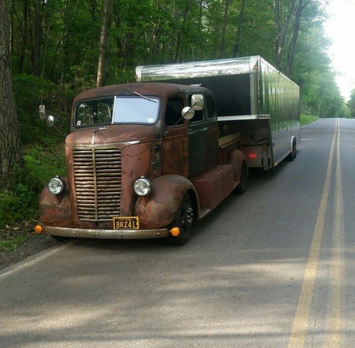 an old truck is parked on the side of the road in front of some trees