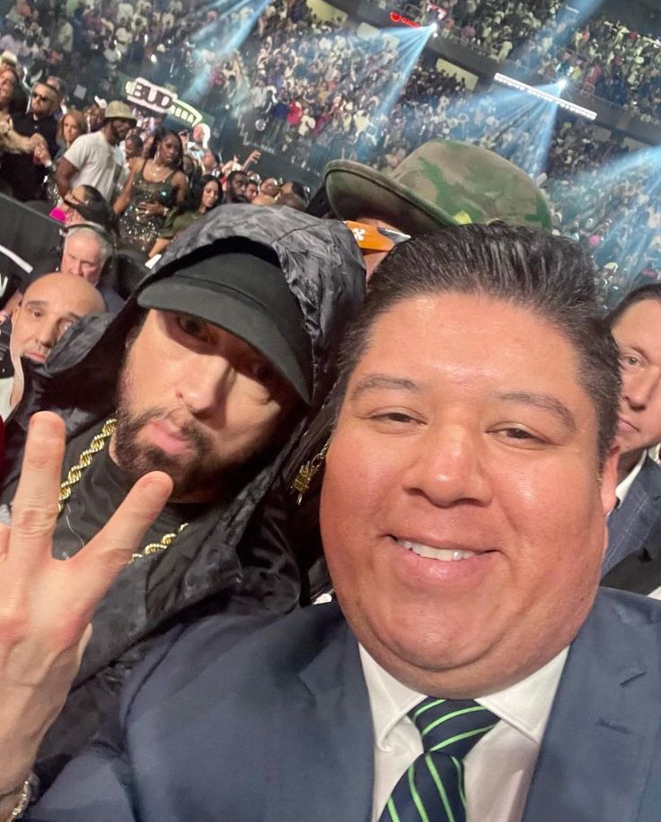 a man in a suit and tie poses for a photo with another man at a sporting event