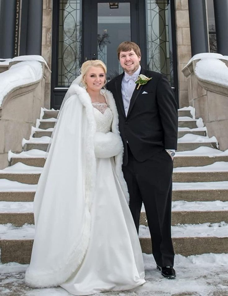 a bride and groom standing in front of a building with snow on the ground outside