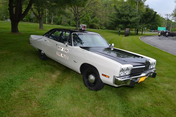 an old police car is parked in the grass