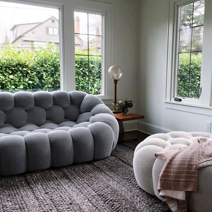 a living room filled with furniture next to two windows and a rug on the floor