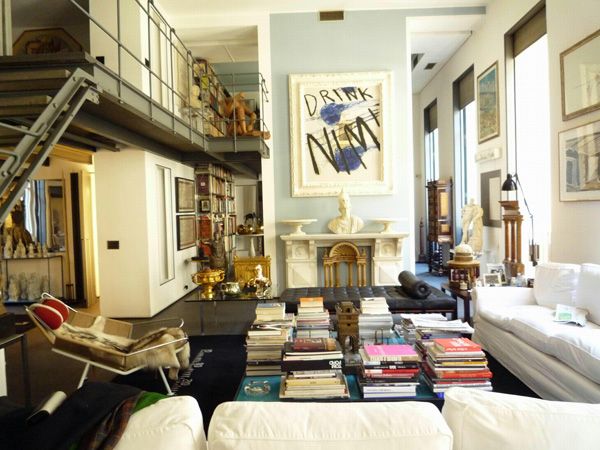 a living room filled with lots of furniture and books on top of a coffee table