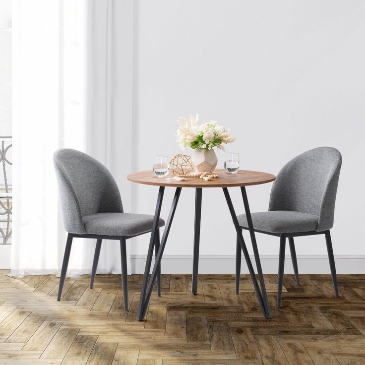 a table with two chairs and a vase on top of it in front of a white wall