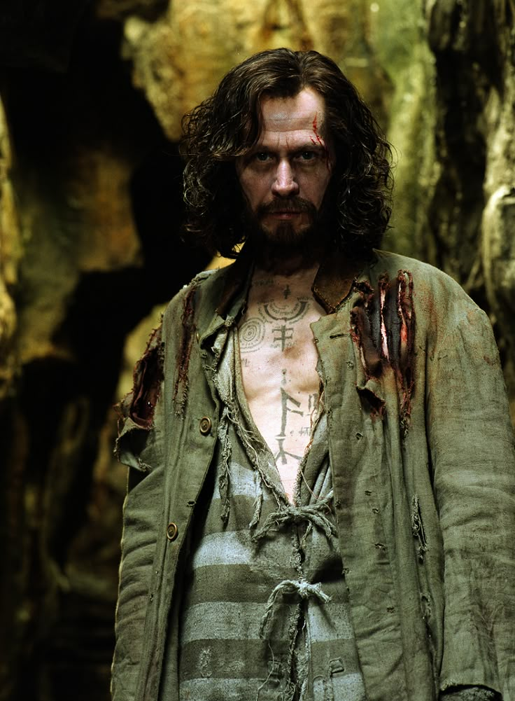 a man with blood all over his face and chest standing in front of a cave