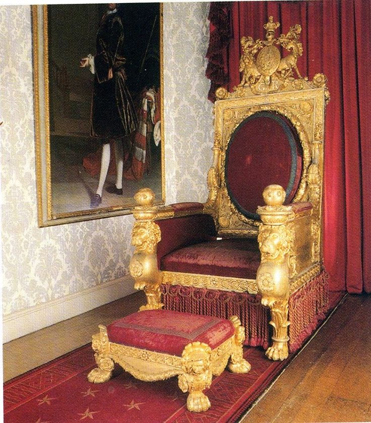 an elaborately decorated chair in front of a mirror and red carpeted flooring