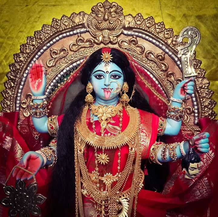 a woman dressed in red and gold with her hands up to the side, holding a spoon