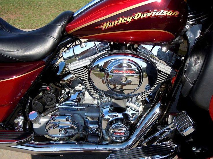 the front end of a red motorcycle parked in a parking lot with grass behind it