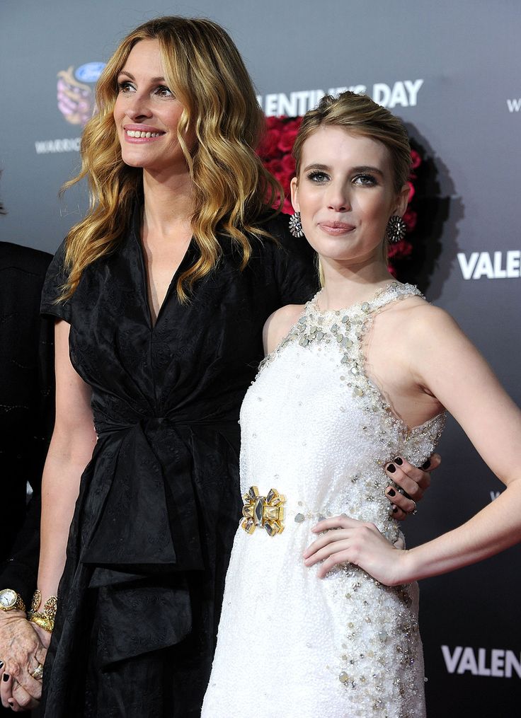 two women standing next to each other on a red carpet