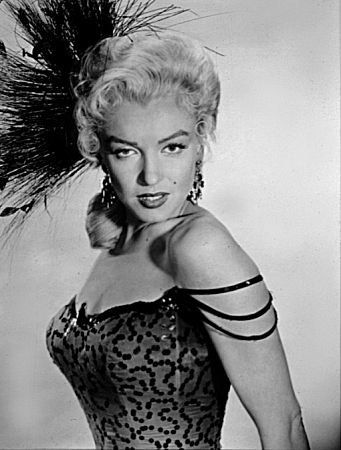 an old black and white photo of a woman in a dress with feathers on her head