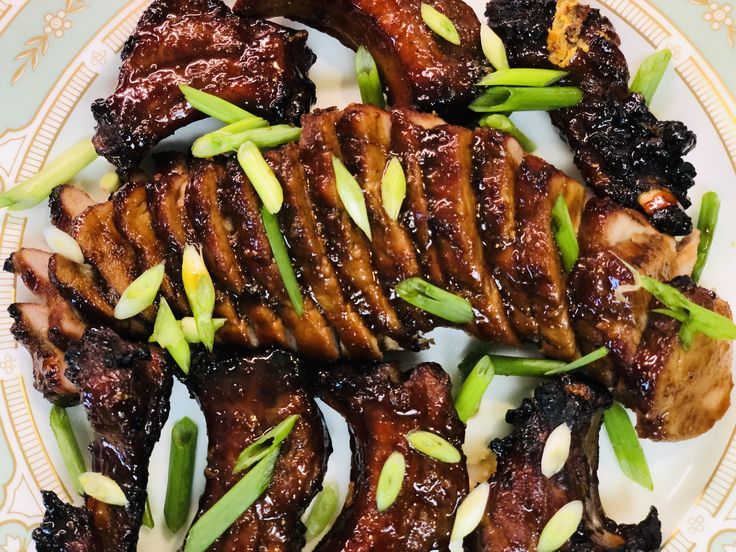 some meat is on a plate with green onions and seasoning sprinkles