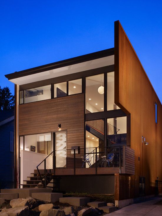 a modern house is lit up at night in the evening with its lights on and stairs leading to the upper level