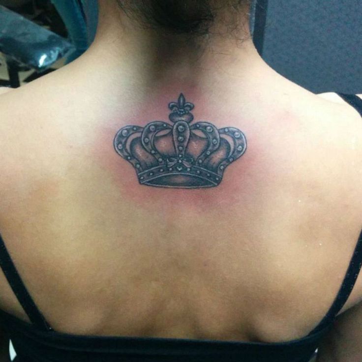 a woman's back with a crown tattoo on her upper arm and chest area