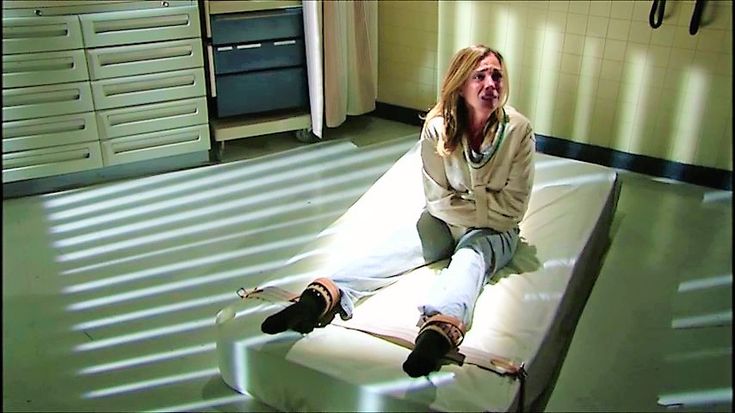 a woman sitting on top of a mattress in a room with lots of drawers and cabinets