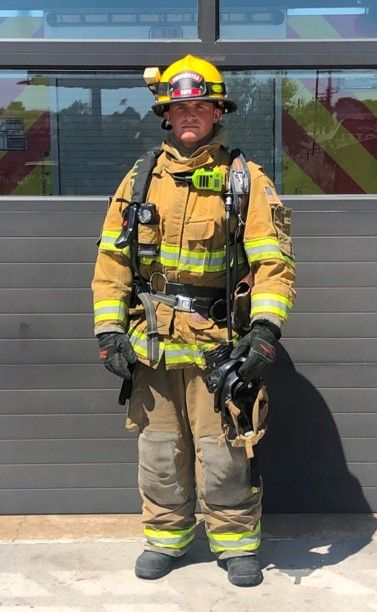 a firefighter standing in front of a building with his gear on and helmet on