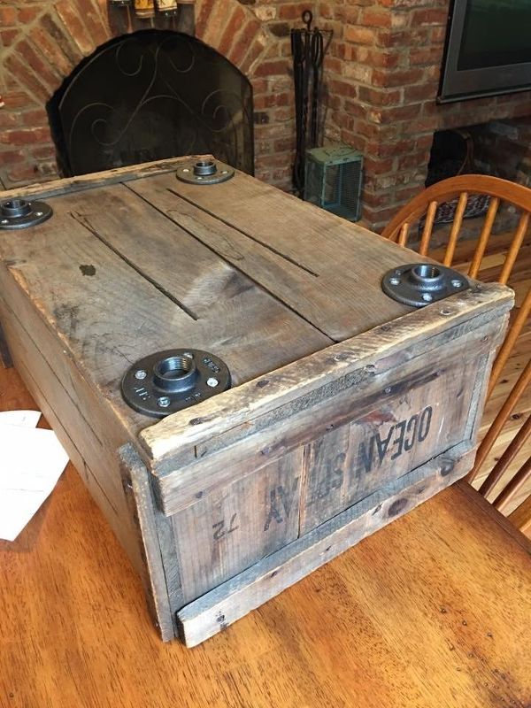 an old wooden box sitting on top of a table in front of a fire place