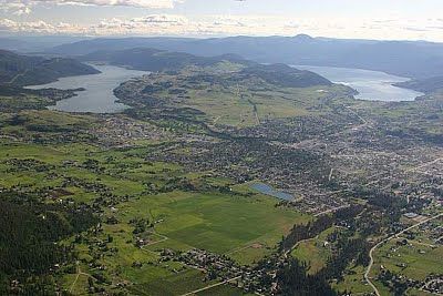 an aerial view of a city and lake in the distance, with mountains in the background