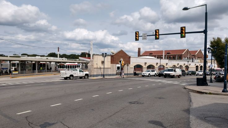 an intersection with traffic lights and cars on the road in front of buildings that have shops