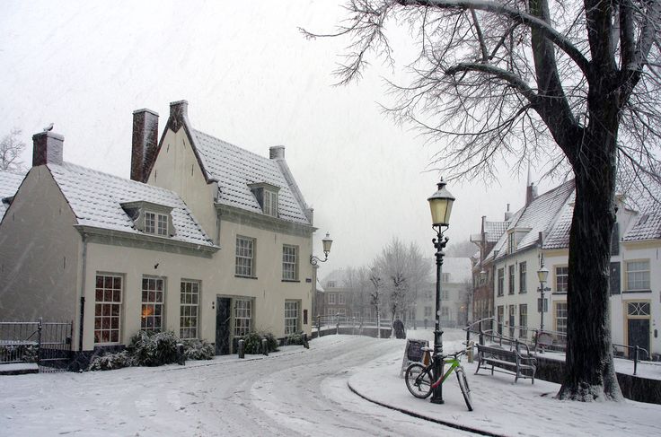 a bike parked on the side of a snow covered road next to a white building