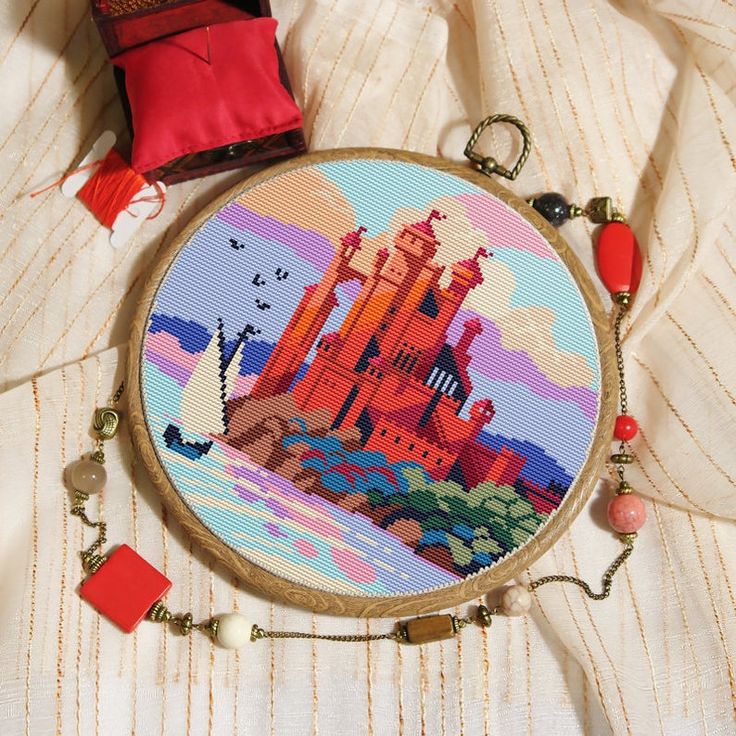 a cross stitch pattern with a castle in the background and a red bag on top