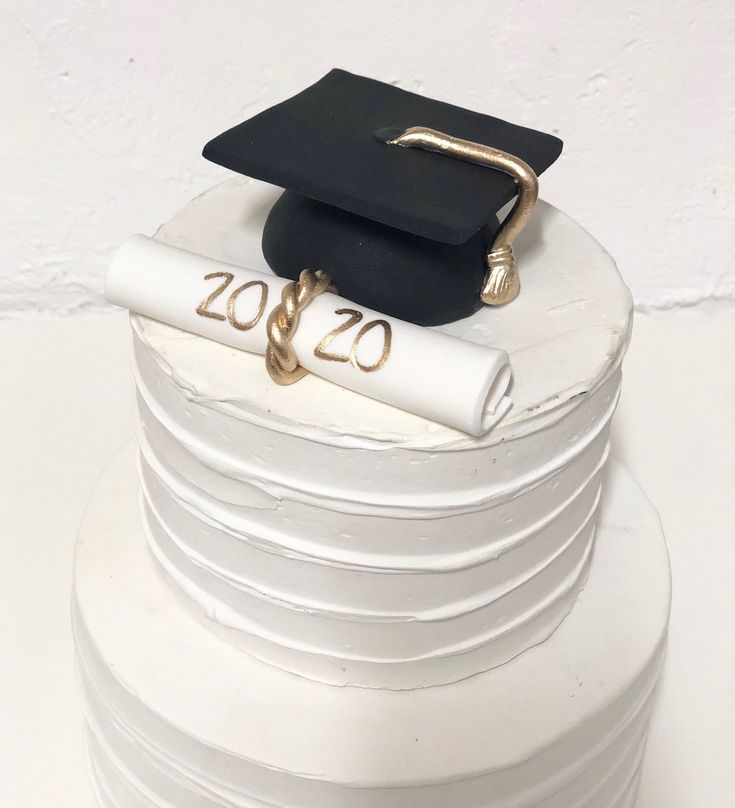 a graduation cap and diploma on top of stacks of white cake plates with gold lettering