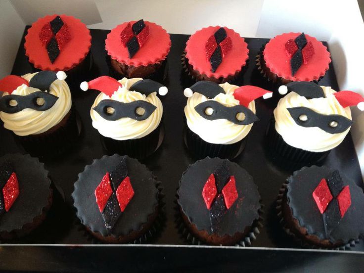 cupcakes with red and black frosting are arranged in a box on a table