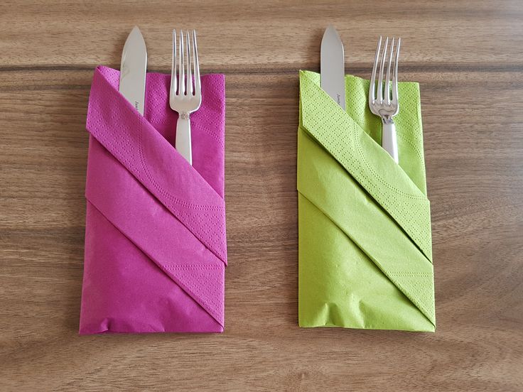 two napkins with forks on them are sitting next to each other in front of a wooden table