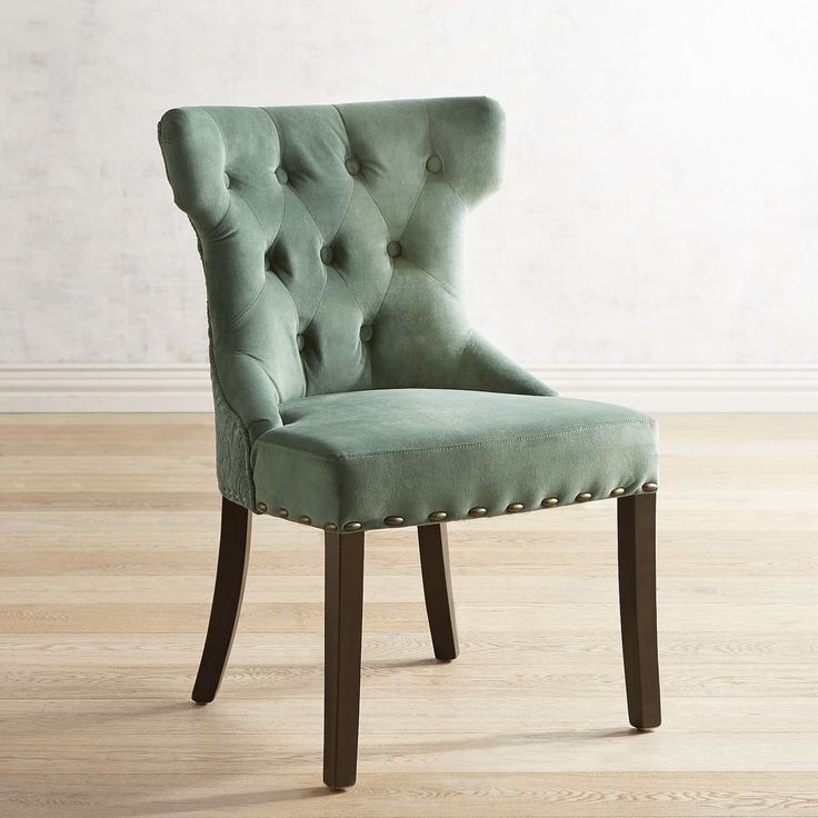 a green chair sitting on top of a hard wood floor next to a white wall