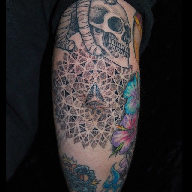 a man's arm with tattoos and a skull in the middle, on which he is wearing a black t - shirt