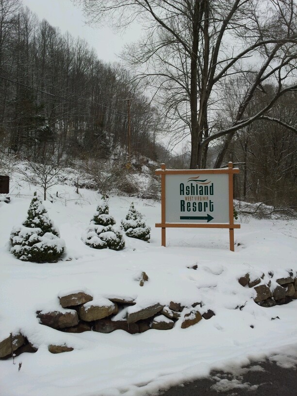 a sign that is in the snow by some rocks and trees with no leaves on it