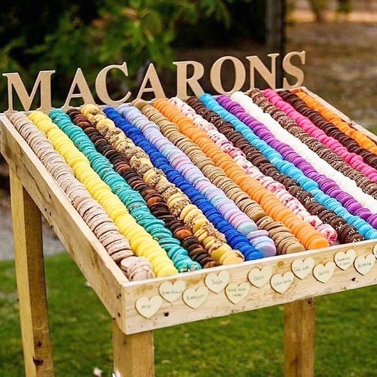 macaroons are arranged on a wooden stand in the grass near a sign that says macaroons