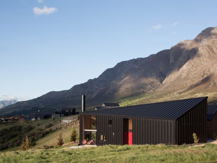 there is a black building on the side of a hill with mountains in the background