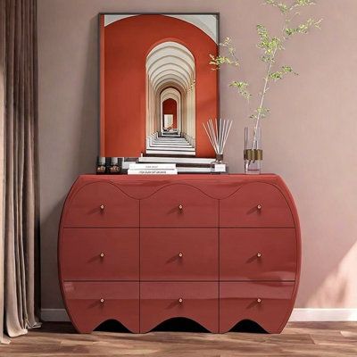 a red dresser with an art piece on top